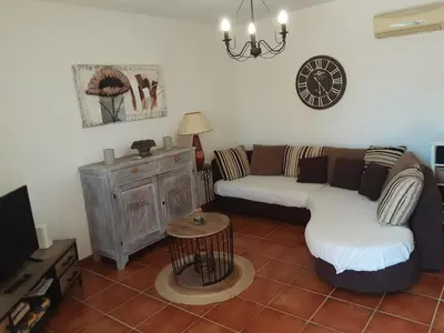a living room with a couch and a clock on the wall at La Palombière - L Arbousier in Casalabriva