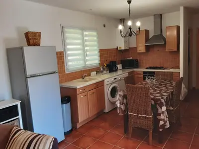 a kitchen with a white refrigerator and a table with chairs at La Palombière - L Arbousier in Casalabriva