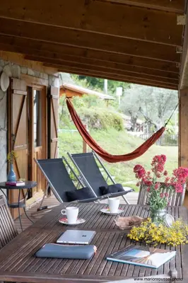 a wooden table with chairs and flowers on a deck at Oliveraie d'Olmiccia in Olmiccia