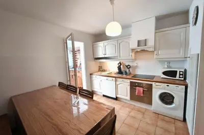 a kitchen with white cabinets and a wooden table at Bright apartment with two bedrooms in Ajaccio in Cauro