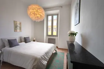 a bedroom with a large bed and a vase of flowers at Bright T3 in the heart of Ajaccio with port view in Ajaccio