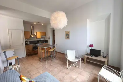 a living room with a kitchen with a table and chairs at Bright T3 in the heart of Ajaccio with port view in Ajaccio