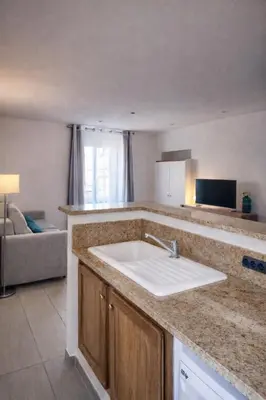 a kitchen with a sink and a living room at Studio vue mer - Centre Ajaccio - 150 m cœur de ville in Ajaccio