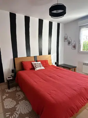 a bedroom with a red bed with black and white stripes at Mini villa residence 3 étoiles Cervione in Cervione
