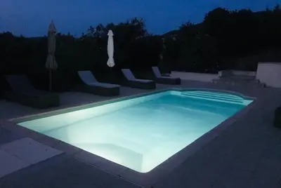 a swimming pool lit up at night at Villa de charme et plage 5 mn à pied in Campomoro