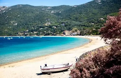 a boat sitting on a beach next to the water at Villa de charme et plage 5 mn à pied in Campomoro