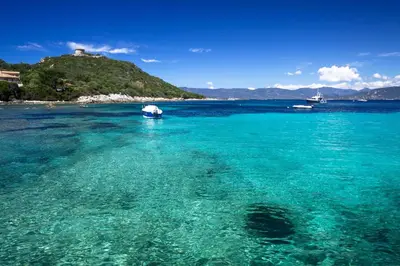 a boat in the water with a hill in the background at Villa de charme et plage 5 mn à pied in Campomoro