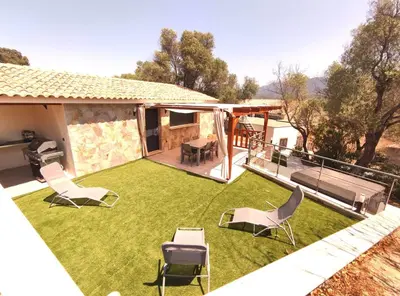 a backyard with a lawn with chairs and a table at Maison a Porto Pollo Corse du sud in Serra-di-Ferro