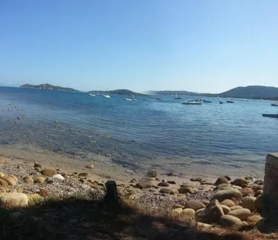 a beach with rocks and boats in the water at un oasi nel verde in Vaccili