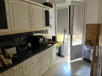 a kitchen with white cabinets and a black counter top at Appartement Ajaccio in Ajaccio