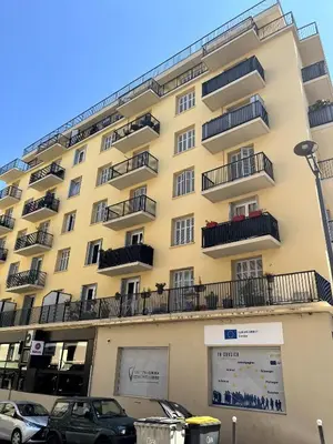 a yellow building with balconies and cars parked in front at Appartement Ajaccio in Ajaccio