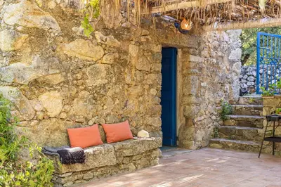 a stone wall with a bench with two orange pillows at Casa U Quercitellu Ville-di-Paraso in Ville-di-Paraso