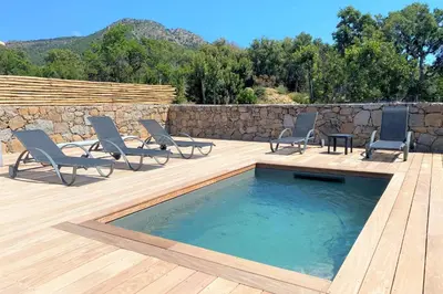 a patio with chairs and a pool and a wall at Villa Oliu Di Santa Lucia in Conca