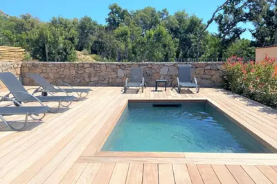 a swimming pool with chairs and a wooden deck at Villa Oliu Di Santa Lucia in Conca