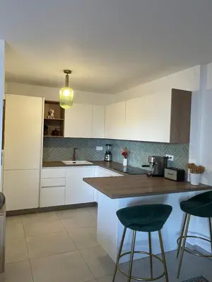 a kitchen with white cabinets and a counter with stools at Charming Apartment Ajaccio in Ajaccio