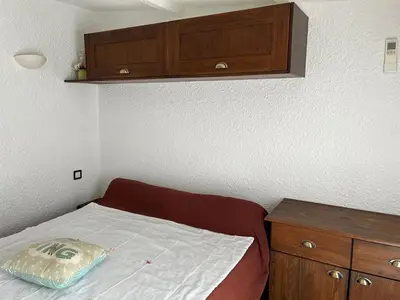 a small bedroom with a bed and a wooden cabinet at Maisonnette privé bord de mer Poggio mezzana in Poggio-Mezzana