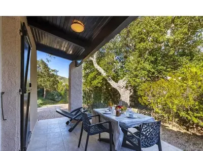 a table and chairs on a patio with a tree at Villa Lavezzi F2 2-4 pers Rondinara, Bonifacio in Bonifacio
