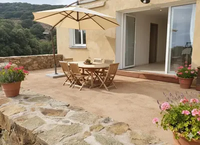 a patio with a table and an umbrella at location Appartement Cargèse in Cargèse