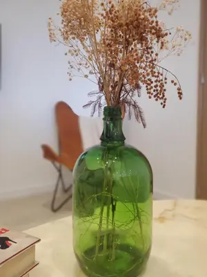 a green vase with dried flowers in it on a table at location Appartement Cargèse in Cargèse
