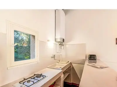 a white kitchen with a sink and a window at Villa Cala Rossa 45M2 4-5 pers Rondinara Bonifacio in Bonifacio