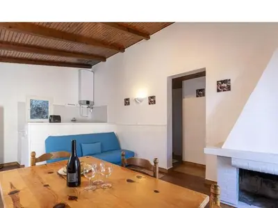 a dining room with a table and a blue couch at Villa Cala Rossa 45M2 4-5 pers Rondinara Bonifacio in Bonifacio