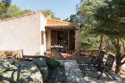 a house with two chairs and a table in front of it at Villa Folaca 45m2 5 pers Rondinara Bonifacio in Bonifacio