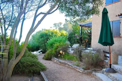 a garden with a green umbrella next to a building at Villa 65m2 7 pers - Rondinara, Bonifacio in Bonifacio