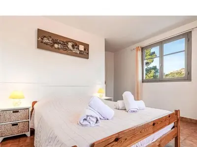 a bedroom with a bed with white sheets and a window at Villa 65m2 7 pers - Rondinara, Bonifacio in Bonifacio