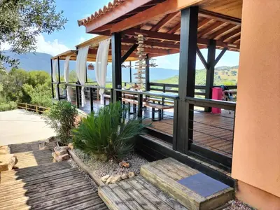 a house with a deck with a table and surfboards at JARDIN de PRATAVONE in Cognocoli-Monticchi