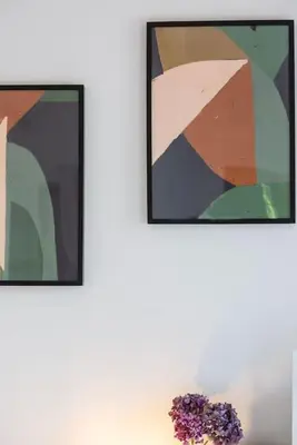 two framed paintings on a wall with a vase of flowers at Les Hameaux De Buttaciolo in Cuo