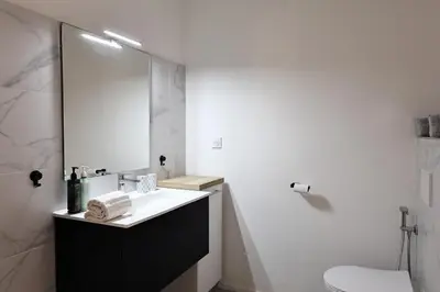 a white bathroom with a sink and a mirror at Filori - T2 avec piscine chauffée et plage privée in Pianottoli-Caldarello
