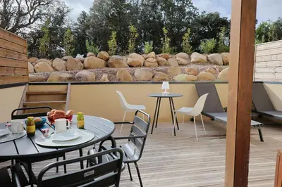 a patio with two tables and chairs on a deck at Filori - T2 avec piscine chauffée et plage privée in Pianottoli-Caldarello