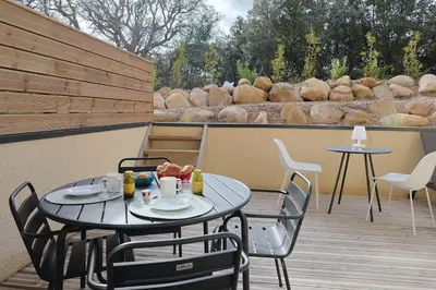 a patio with two tables and chairs on a deck at Filori - T2 avec piscine chauffée et plage privée in Pianottoli-Caldarello