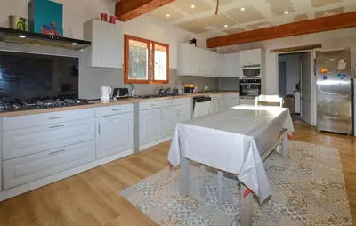 a kitchen with white cabinets and a table in it at Grande Villa Piscine in Evisa