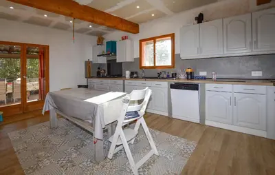 a kitchen with white cabinets and a table and chairs at Grande Villa Piscine in Evisa