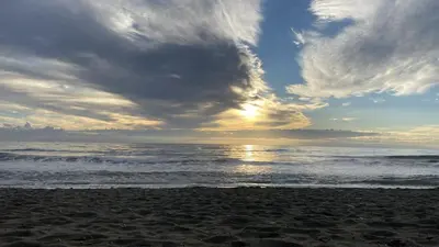 a beach with a cloudy sky and the ocean at La villa Emmagathe in Poggio-Mezzana