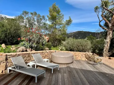 a patio with two chairs and a table and a tub at Casetta di Asciaghju, suite avec jacuzzi privé et accès direct aux plages in Porto-Vecchio