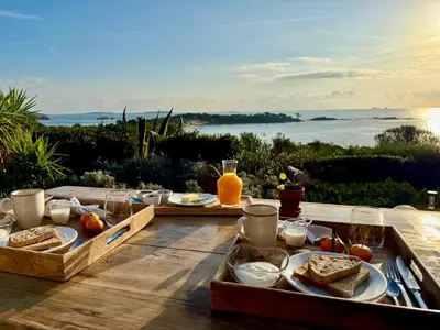 a picnic table with food and a view of the ocean at Casetta di Asciaghju, suite avec jacuzzi privé et accès direct aux plages in Porto-Vecchio