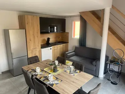a kitchen and dining room with a table and a couch at Mini Villa - Les Hameaux de Saint Cyprien in Lecci