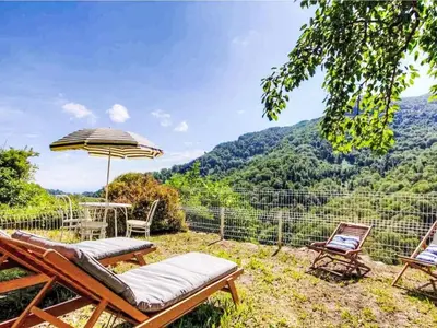 a patio with two chairs and an umbrella at Maison entre mer et montagne in Santa-Reparata-di-Moriani