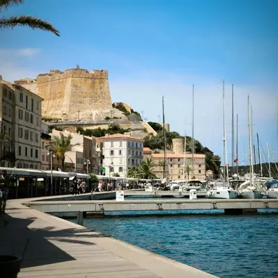 a marina with boats and a castle in the background at Port de Bonifacio in Bonifacio