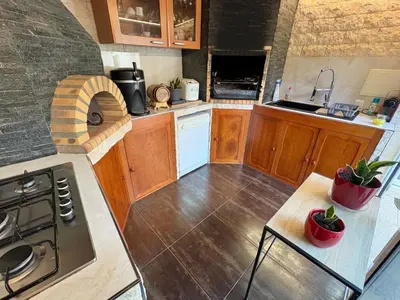 a kitchen with wooden cabinets and a stove top oven at Villa avec piscine 8 personnes in Porto-Vecchio