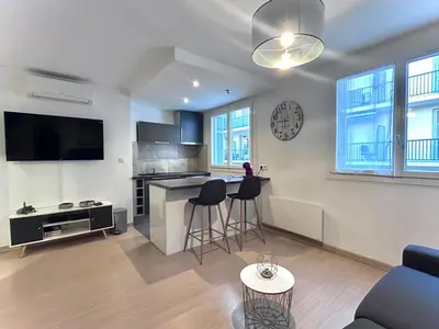 a living room with a kitchen with a counter and stools at Studio climatisé au cœur d Ajaccio - à pied des plages et du centre in Ajaccio