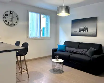 a living room with a black couch and a table at Studio climatisé au cœur d Ajaccio - à pied des plages et du centre in Ajaccio