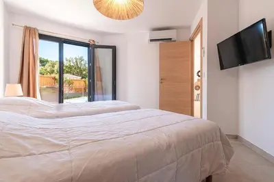 a bedroom with a large bed and a flat screen tv at Villa U Veniqui 2 - Piscine privée in Conca