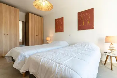 a white bedroom with two beds and a chandelier at Villa U Veniqui 2 - Piscine privée in Conca