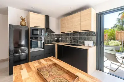 a kitchen with black appliances and wooden cabinets at Villa U Veniqui 2 - Piscine privée in Conca