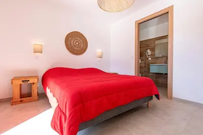 a bedroom with a red bed and a bathroom at Villa U Veniqui 1 - Piscine privée in Conca