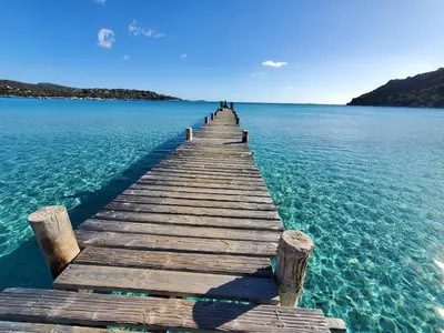 a wooden pier in the middle of the water at Mini villa 200 mètres de la plage de Santa Guilia in Porto-Vecchio