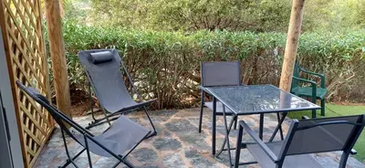 three chairs and a glass table on a patio at Mini villa 200 mètres de la plage de Santa Guilia in Porto-Vecchio